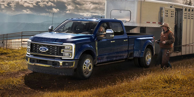 Blue Ford Super Duty truck towing a trailer in a scenic outdoor setting showcasing its towing capability.