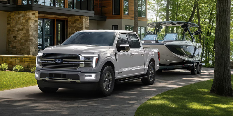 White Ford F-150 towing a boat parked outside a modern home.